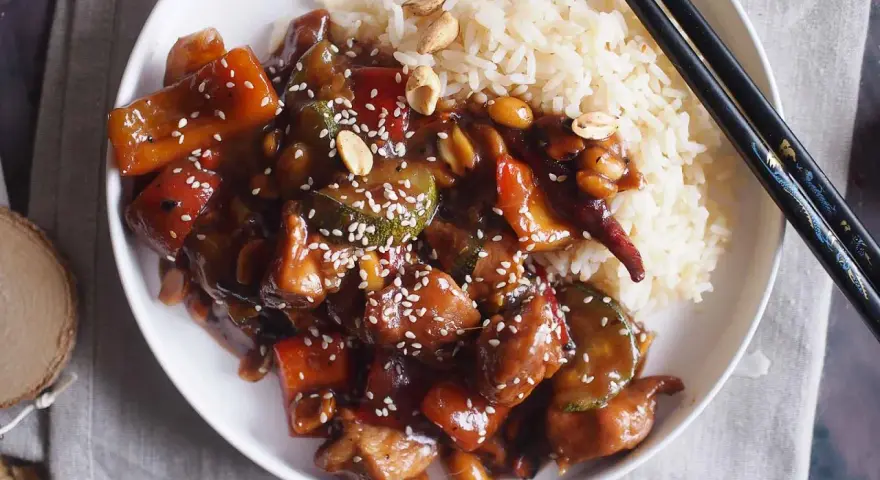 Pyszne danie kung pao z kurczakiem, warzywami i orzeszkami ziemnymi, podane z ryżem.