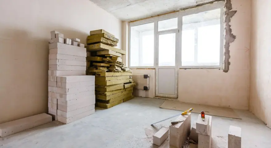 Materiały budowlane, w tym pustaki i wełna mineralna, czekają na **ocieplenie ścian od wewnątrz**.