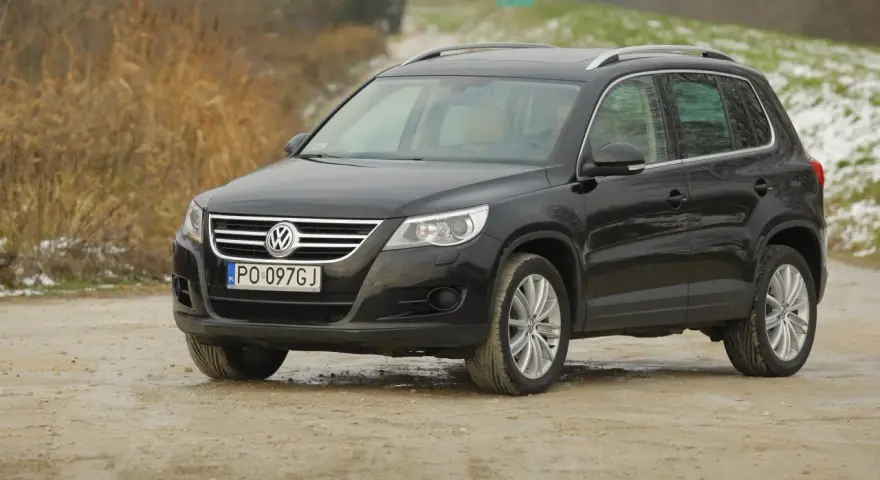 Czarny Volkswagen Tiguan, jeden z najmniej awaryjnych SUV-ów 10 letnich, na drodze gruntowej.