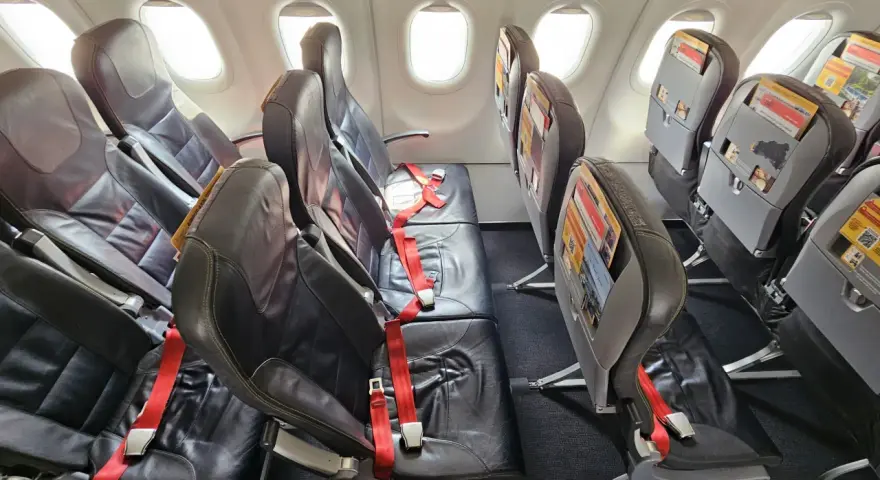 Puste fotele w samolocie, czerwone pasy bezpieczeństwa. Czy warto lecieć Pegasus Airlines? Opinie pasażerów są różne.