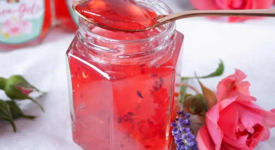Ein Glas Sylter Rosenmarmelade, verziert mit Rosen und Lavendel. Ein köstliches Rezept für den Sommer.