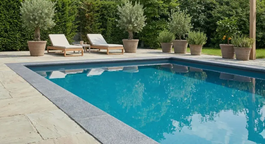 Luxuriöser Pool mit Steinumrandung und mediterranen Pflanzen. Tolle pool verkleiden ideen für eine elegante Poollandschaft.