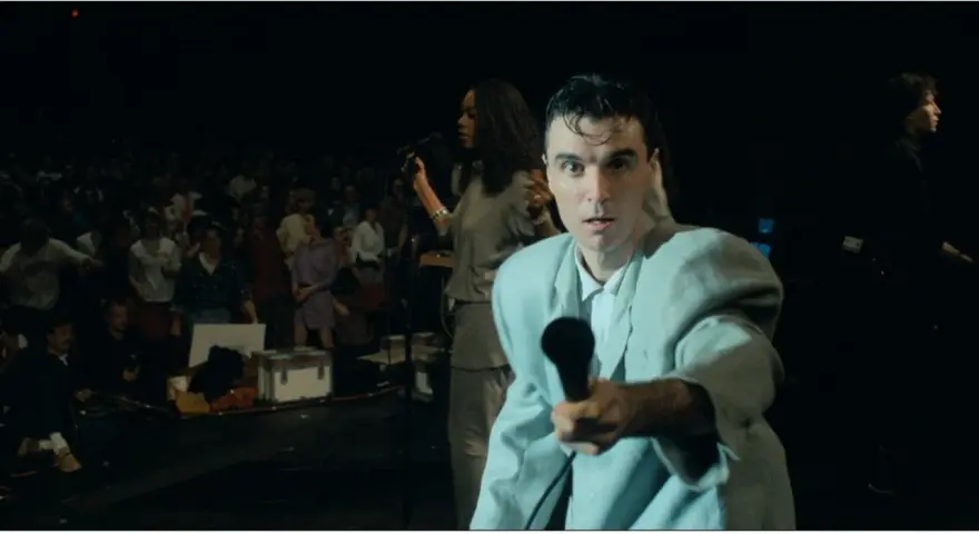 David Byrne z The Cult - Be Free, śpiewa do mikrofonu na tle tłumu.