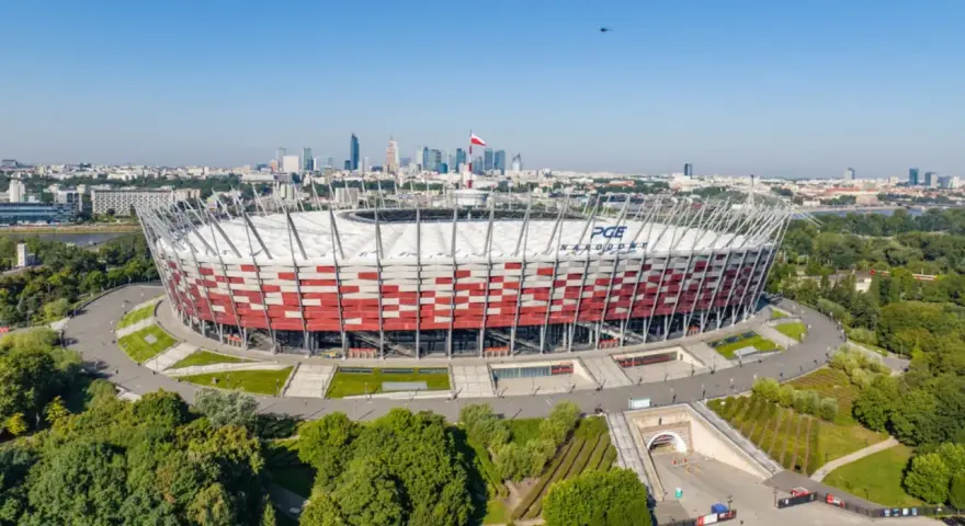 PGE Narodowy, jeden z największych stadionów w Polsce, w otoczeniu zieleni i warszawskiej panoramy.