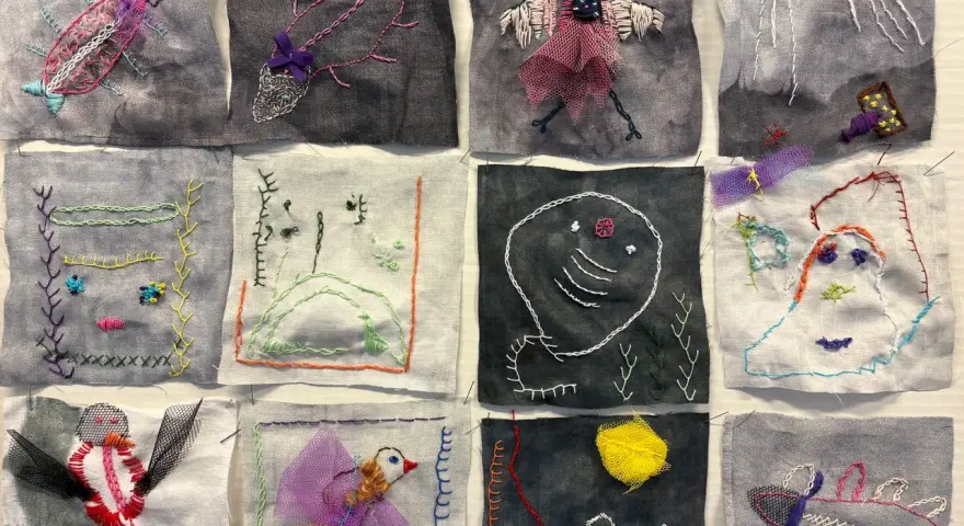 En bilduppgift vår med broderade figurer: insekter, fåglar, ansikten och abstrakta former på tygbitar.