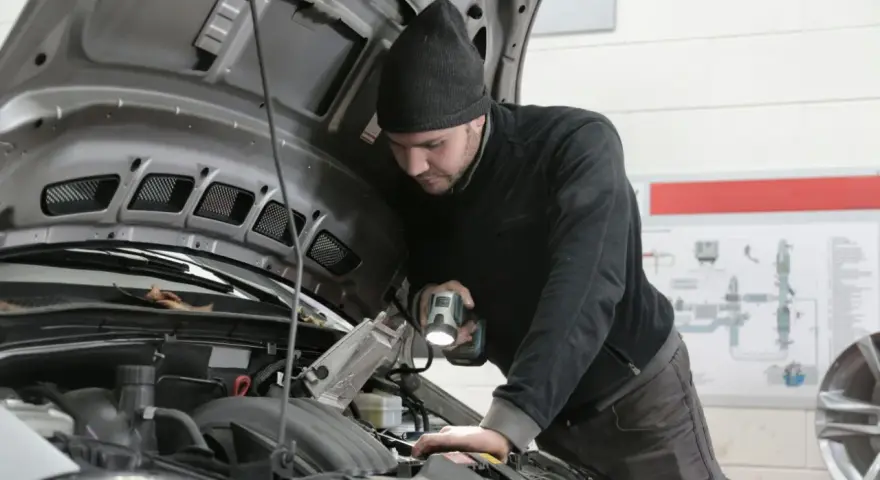 Mechanik z latarką bada silnik Forda, szukając przyczyny błędu DTC P0380.