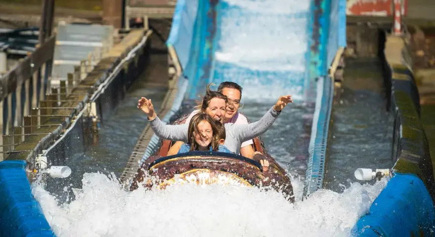 Familie hat Spaß auf einer spritzigen Wasserbahn im Freizeitpark.