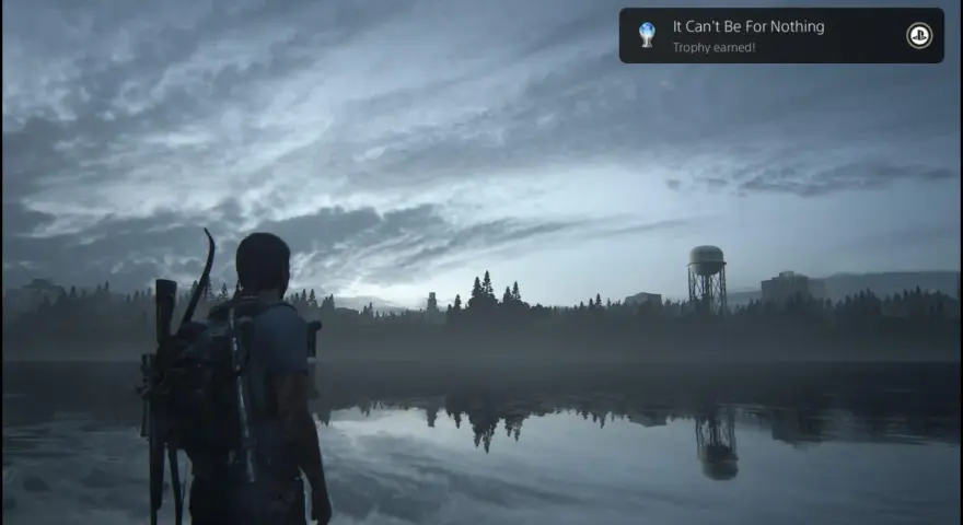 Joel mira un lago tranquilo, con un cartel de "Platino The Last of Us Parte 1" flotando.