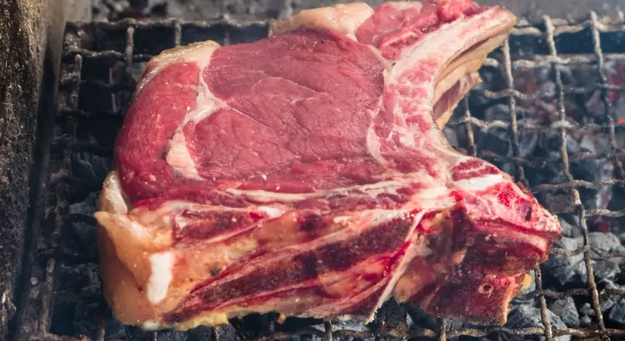 Bistecca alla fiorentina cruda su griglia, pronta per la cottura. Il tempo cottura fiorentina è fondamentale per una perfetta riuscita.