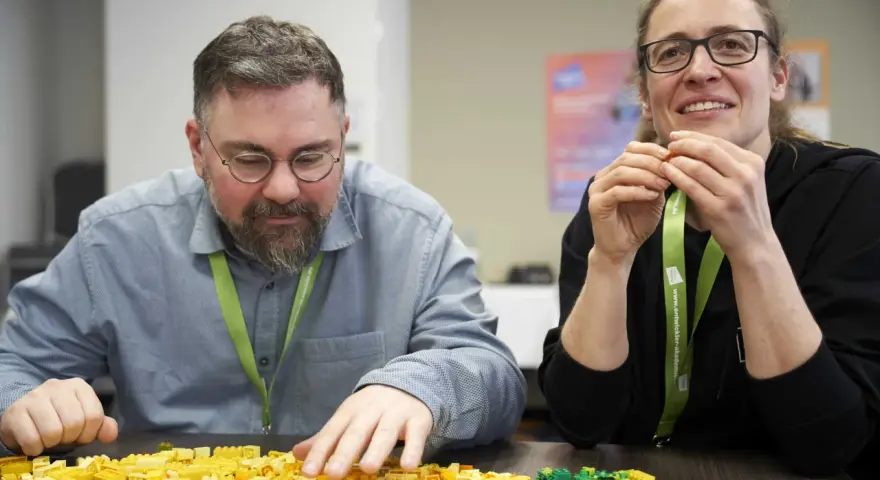 Zwei Personen bauen mit bunten Legosteinen, während sie an einem software architecture summit teilnehmen.
