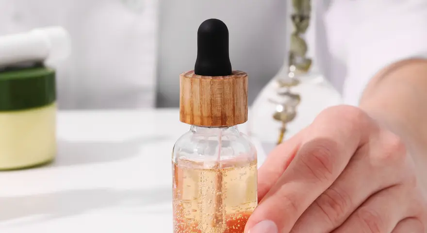 Dłoń trzymająca serum z pipetką. Składniki takie jak EDTA w kosmetykach pomagają stabilizować formuły.