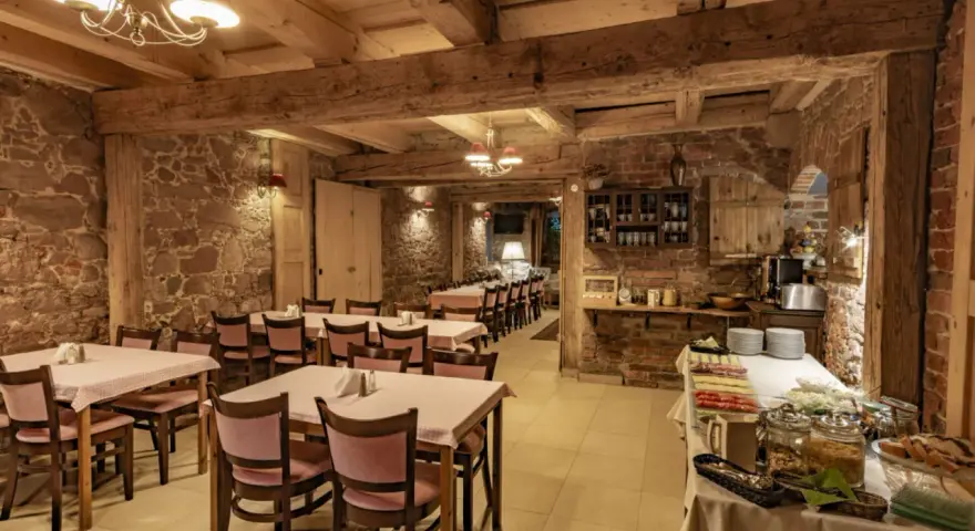 Przytulna restauracja w stylu rustykalnym, z kamiennymi ścianami i drewnianymi belkami. Idealne miejsce na posiłek w twierdzy Srebrna Góra.