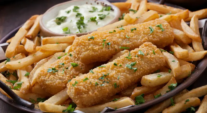 Knusprige Fischstäbchen mit Pommes und Dip. Perfekt paniert ohne Ei, garniert mit Petersilie. Ein Genuss für Groß und Klein.