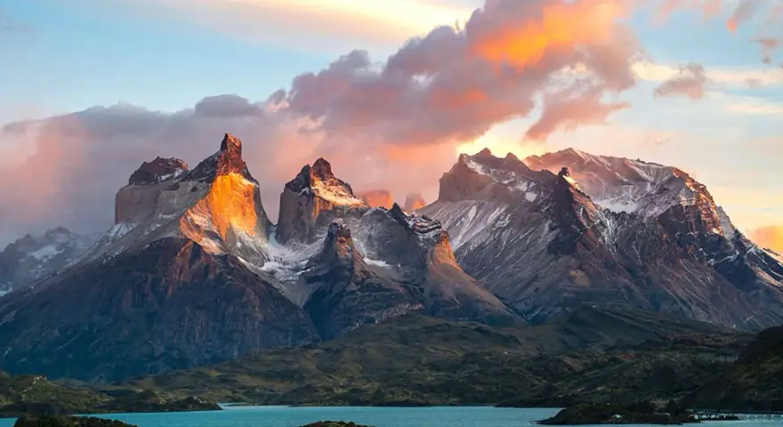 Wspaniała wycieczka do Chile! Słońce oświetla skaliste szczyty Torres del Paine, odbijając się w turkusowym jeziorze.