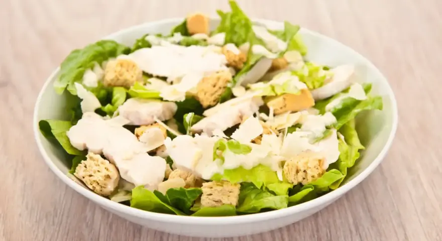 Salade César appétissante avec poulet, croûtons dorés et copeaux de parmesan. Un classique des salade cesar ingredient.