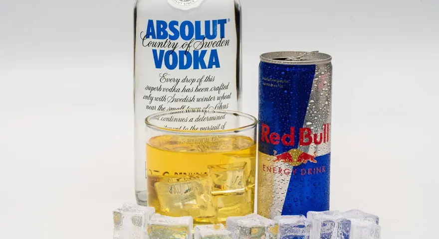 Szklanka z drinkiem, puszka Red Bulla i butelka wódki Absolut – klasyczny energetyk z alkoholem.