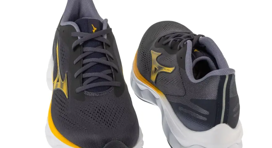 Dwa buty do biegania Mizuno w kolorze grafitowym z żółtymi akcentami. Mizuno to znana firma sportowa.