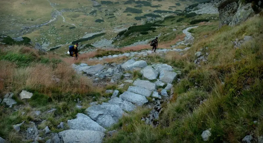 Dwaj turyści wędrują kamienistym szlakiem przez malownicze polskie góry - Tatry.