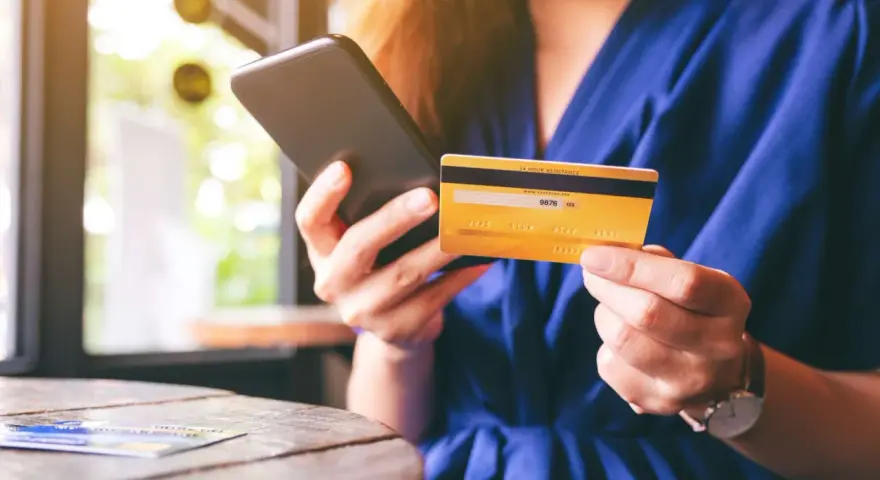 Frau hält Smartphone und goldene Kreditkarte für Online-Shopping.