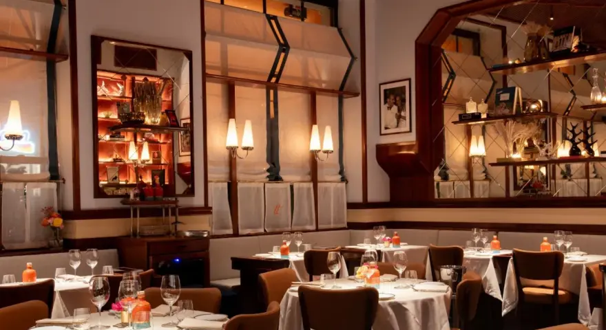 Tavoli apparecchiati in un ambiente elegante, ideale per scoprire i migliori ristoranti Milano. Luci soffuse e dettagli raffinati creano un'atmosfera accogliente.