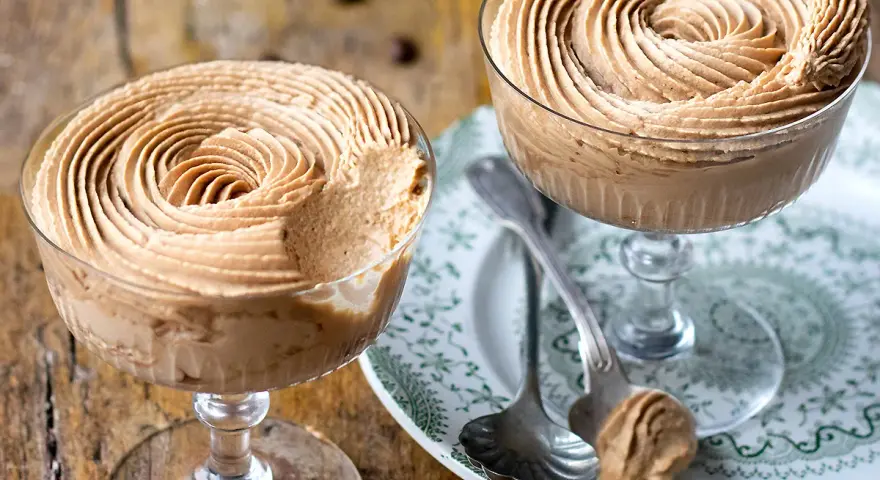 Due coppe di deliziosa mousse al caffè, guarnite a spirale, su un piatto decorato.