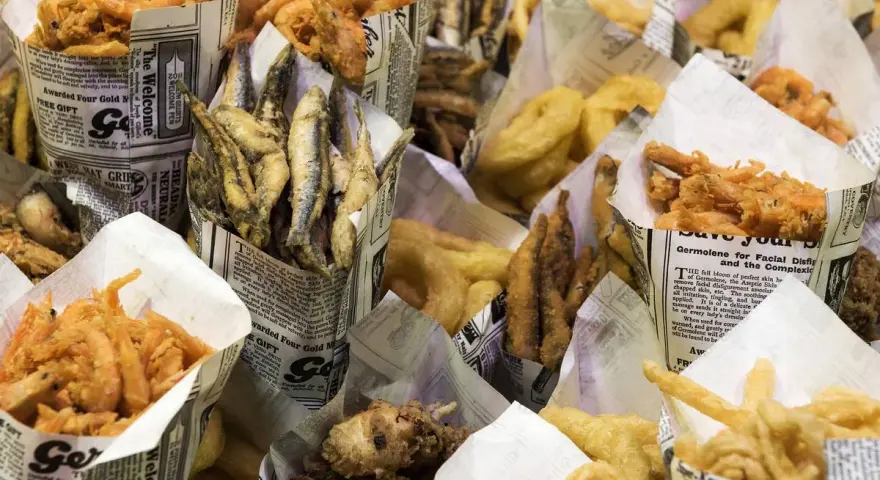 Una variedad de fritura de pescado, incluyendo camarones, boquerones y calamares, servidos en conos de papel.