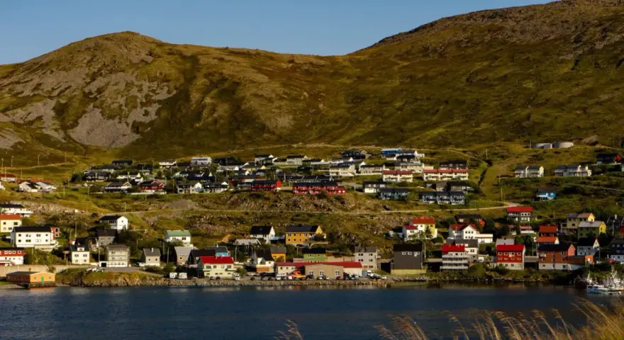 Kolorowe domy nad fiordem, w tle górzysty krajobraz. Nordcamp Norwegia, malownicza wioska rybacka.