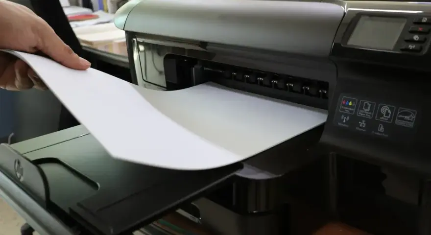 Dłoń wkłada papier do drukarki. To nie jest elementem eksploatacyjnym drukarki laserowej, lecz jej podstawowym materiałem.