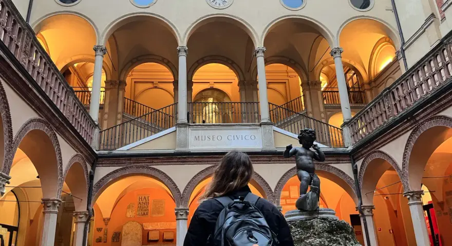 Cortile del Museo Civico, uno dei musei da visitare a Bologna, con una statua di putto e una persona con zaino.