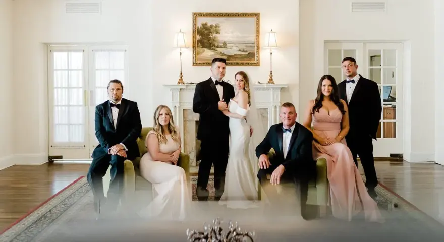 Para ślubna i drużba stoją w eleganckim wnętrzu.