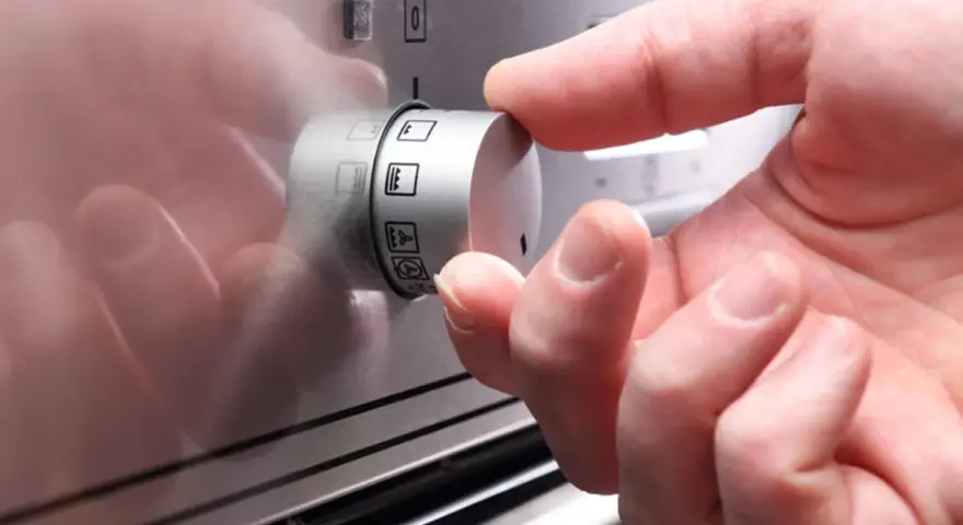 Ein Finger dreht am Drehregler, um die Heizart für den Backofen einzustellen. So funktioniert ein Backofen: Wahl der richtigen Funktion.
