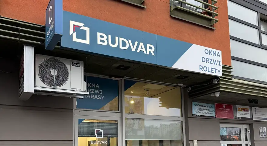 Logo i szyld salonu okien i drzwi "BUDVAR" z napisem "OKNA DRZWI ROLETY".