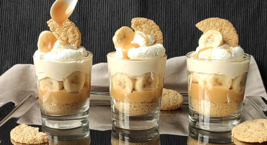 Pyszny deser bananowy przepis w szklaneczkach: warstwy ciastek, karmelu, bananów i bitej śmietany. Idealny na deser!