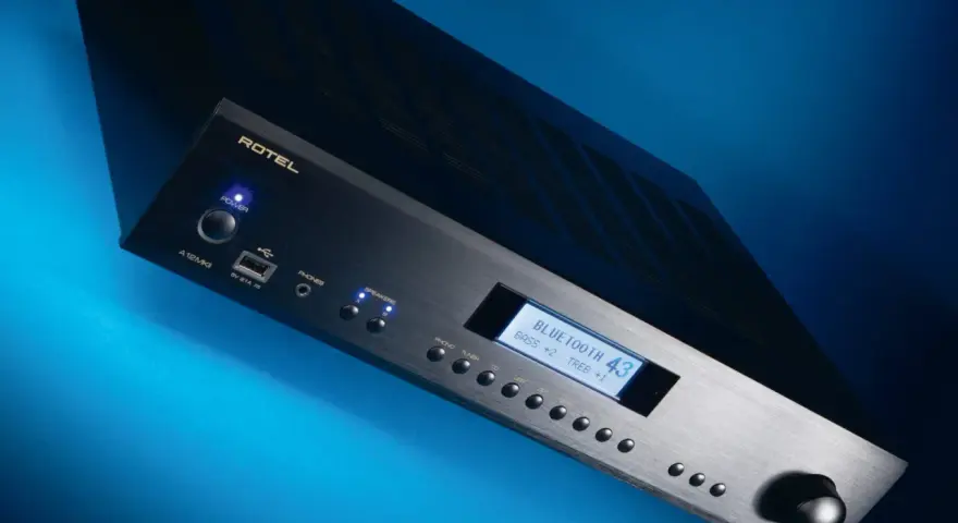 Czarny wzmacniacz Rotel A12 MKII z niebieskim podświetleniem, wyświetlaczem Bluetooth i pokrętłem głośności.