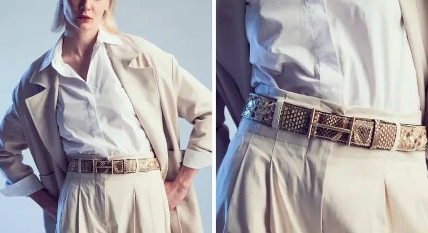 Modello indossa una cintura in pelle di serpente, un accessorio di tendenza che completa un look elegante con pantaloni beige e blazer.