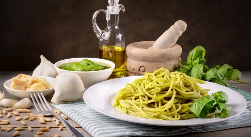 Pyszny makaron z pesto ze słoika, podany z bazylią, czosnkiem, parmezanem i orzeszkami pinii.