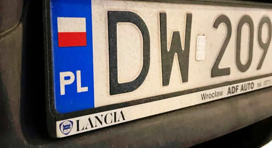Tablica rejestracyjna z napisem "DW 209" i flagą Polski. Zsd rejestracja Lancia z Wrocławia.