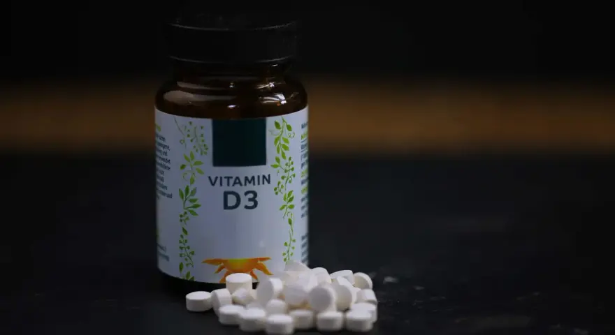Flasche mit Vitamin D3 und Pillen. Wann einnehmen? Am besten mit einer Mahlzeit, um die Aufnahme zu verbessern.
