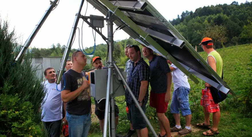 Uczestnicy kursu fotowoltaika montują panele słoneczne. Grupa mężczyzn przygląda się konstrukcji.