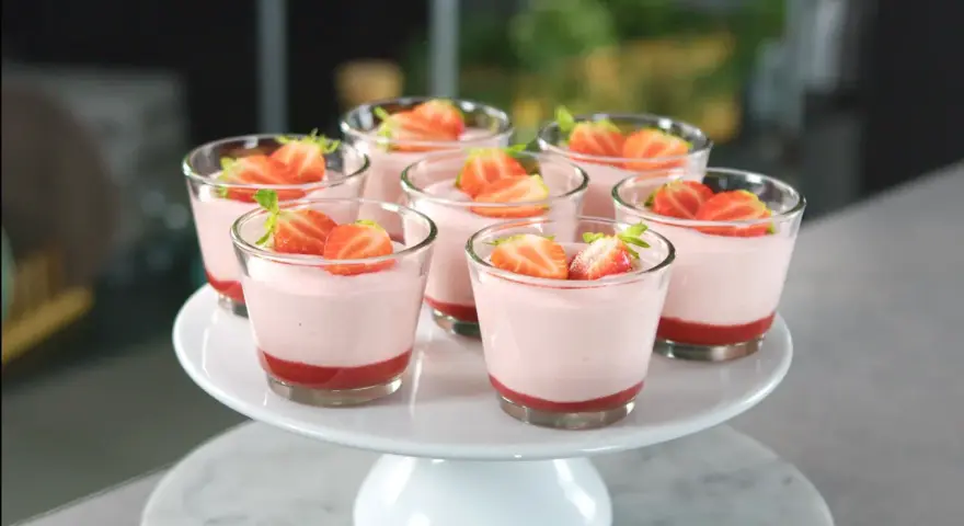 Deliziosi dolci al cucchiaio alla fragola, serviti in bicchierini trasparenti e guarniti con fragole fresche.