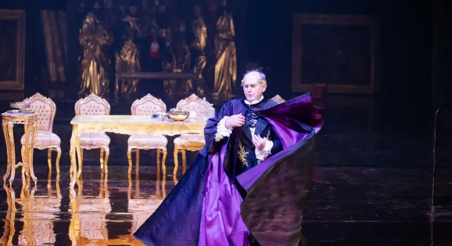 Aktor w purpurowej pelerynie, w teatralnej scenografii, budzi pytanie: misterium co to?