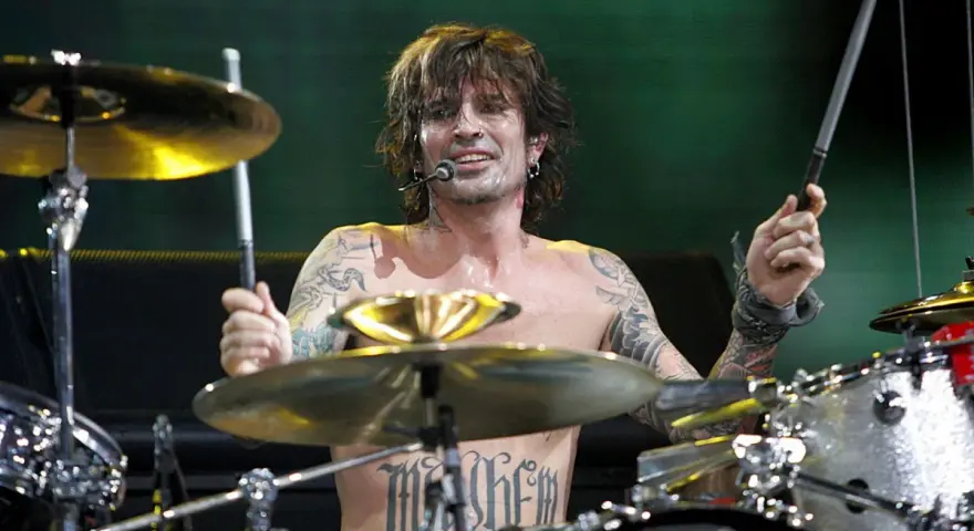Tommy Lee, batteur du groupe, frappe sur sa batterie, torse nu, tatoué, en plein concert.