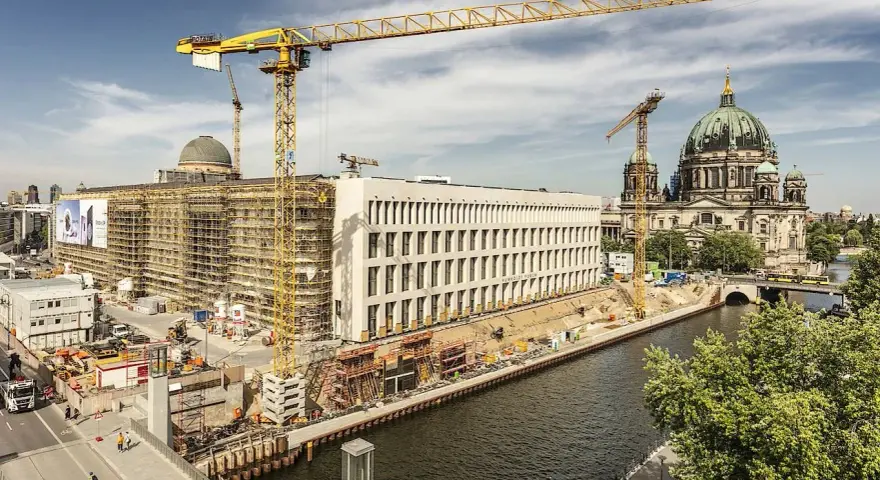 Baustelle am Berliner Dom, Kräne ragen in den Himmel. Ein neues Gebäude entsteht, während der Dom in seiner Pracht erstrahlt. Ein Blick auf das heutige Berlin, das sich ständig neu erfindet.