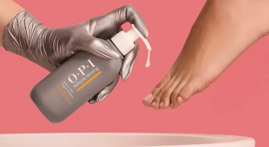 Gloved hand dispenses OPI Nature Strong Pedi Soak, preparing to soak feet for a luxurious pedicure.