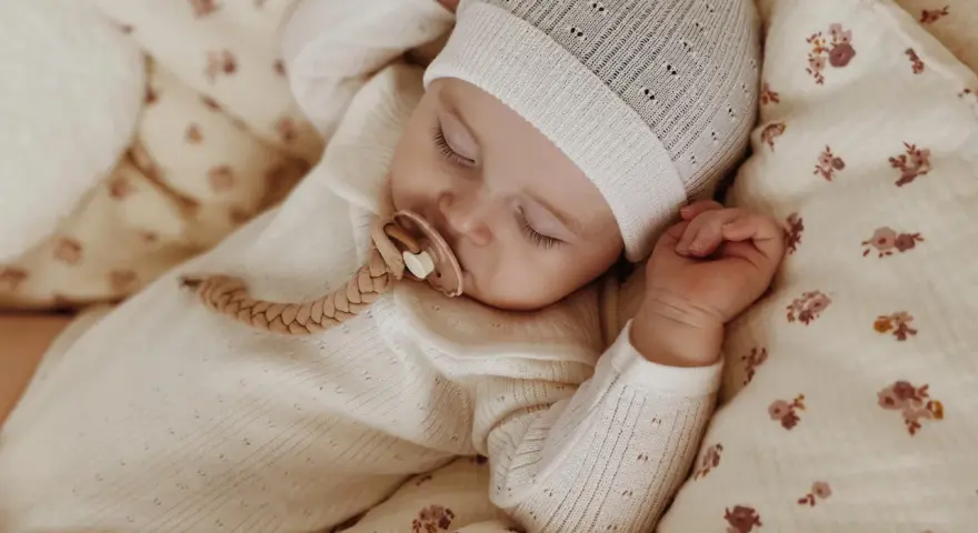 Śpiące dziecko w czapce i pajacyku z wełny merino. Czy wełna merino gryzie? Nie, jest miękka i delikatna dla skóry maluszka.