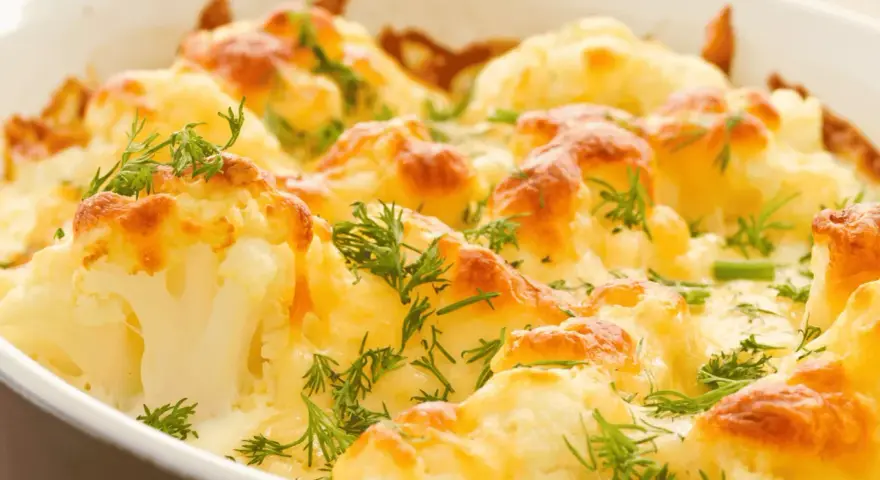 Coliflor al horno gratinada con queso y hierbas frescas. Un plato reconfortante y delicioso.
