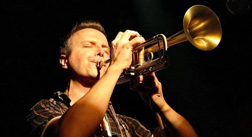 Muzyk gra na trąbce, zamykając oczy. Czy to synkopa co to? Muzyka jazzowa.
