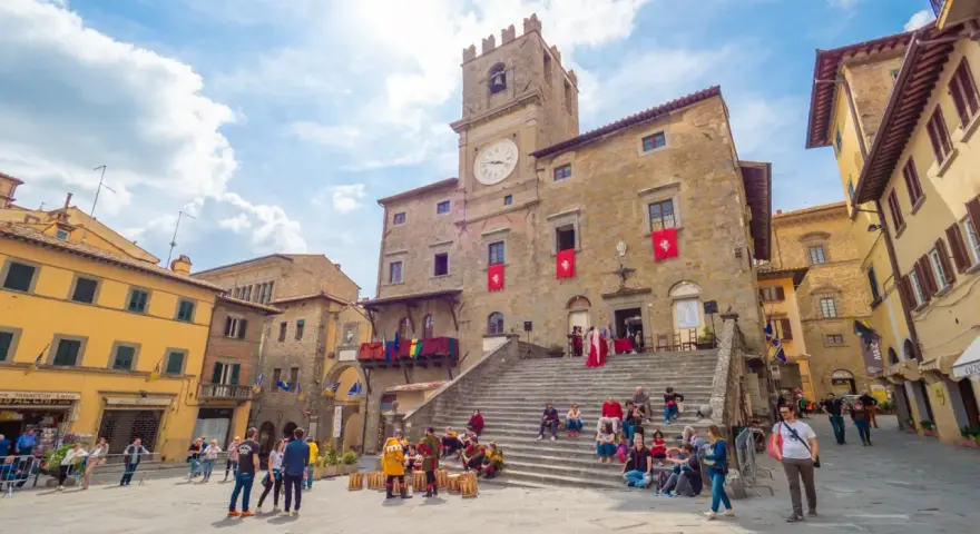 Piazza del Popolo a Cortona, dove si trova questo antico palazzo con torre dell'orologio, animata da turisti e figuranti in costume.