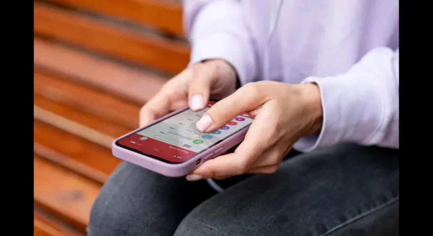 Dłonie kobiety obsługują smartfon, czując subtelne wibracje haptyczne przy każdym dotknięciu ekranu.