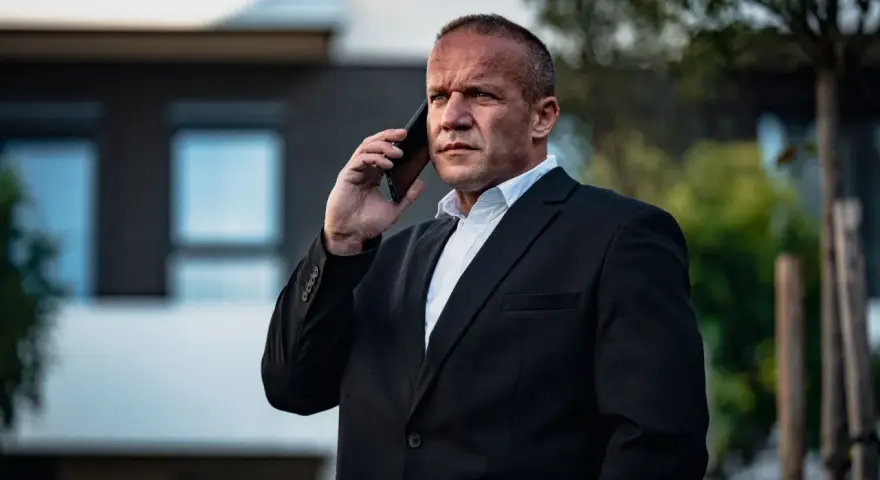 Krzysztof Bukowski, reżyser, w garniturze rozmawia przez telefon.